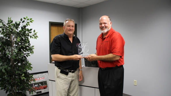 Takeuchi US president Clay Eubanks presents a plaque to David Pearson left inside sales manager in honor of 30 years with the company