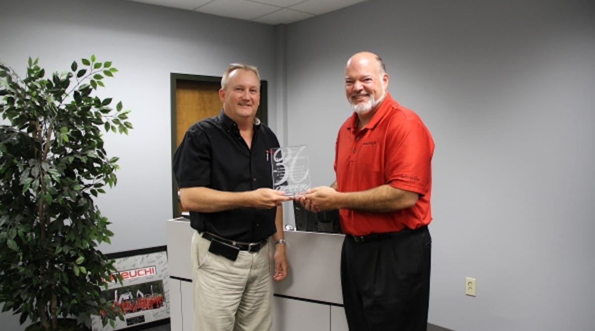 Takeuchi U.S. president Clay Eubanks presents a plaque to David Pearson, left, inside sales manager, in honor of 30 years with the company.