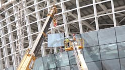 Workers use a Haulotte boomlift for glass installation at Abu Dhabi airport.