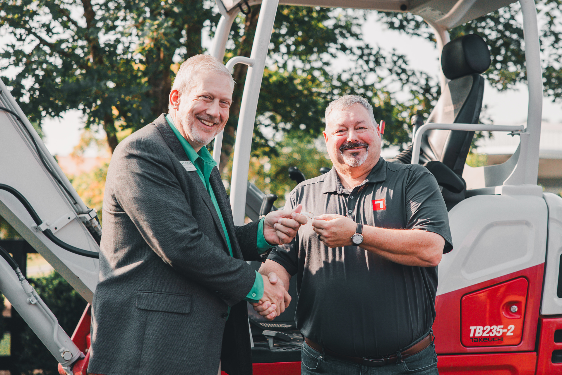 John Uesseler, CEO, Empower College & Career Center, left, receives the key to the excavator from Jeff Stewart, president, Takeuchi-US.