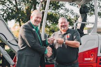 John Uesseler, CEO, Empower College &amp; Career Center, left, receives the key to the excavator from Jeff Stewart, president, Takeuchi-US.