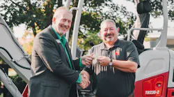 John Uesseler, CEO, Empower College & Career Center, left, receives the key to the excavator from Jeff Stewart, president, Takeuchi-US.