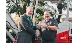 John Uesseler, CEO, Empower College &amp; Career Center, left, receives the key to the excavator from Jeff Stewart, president, Takeuchi-US.