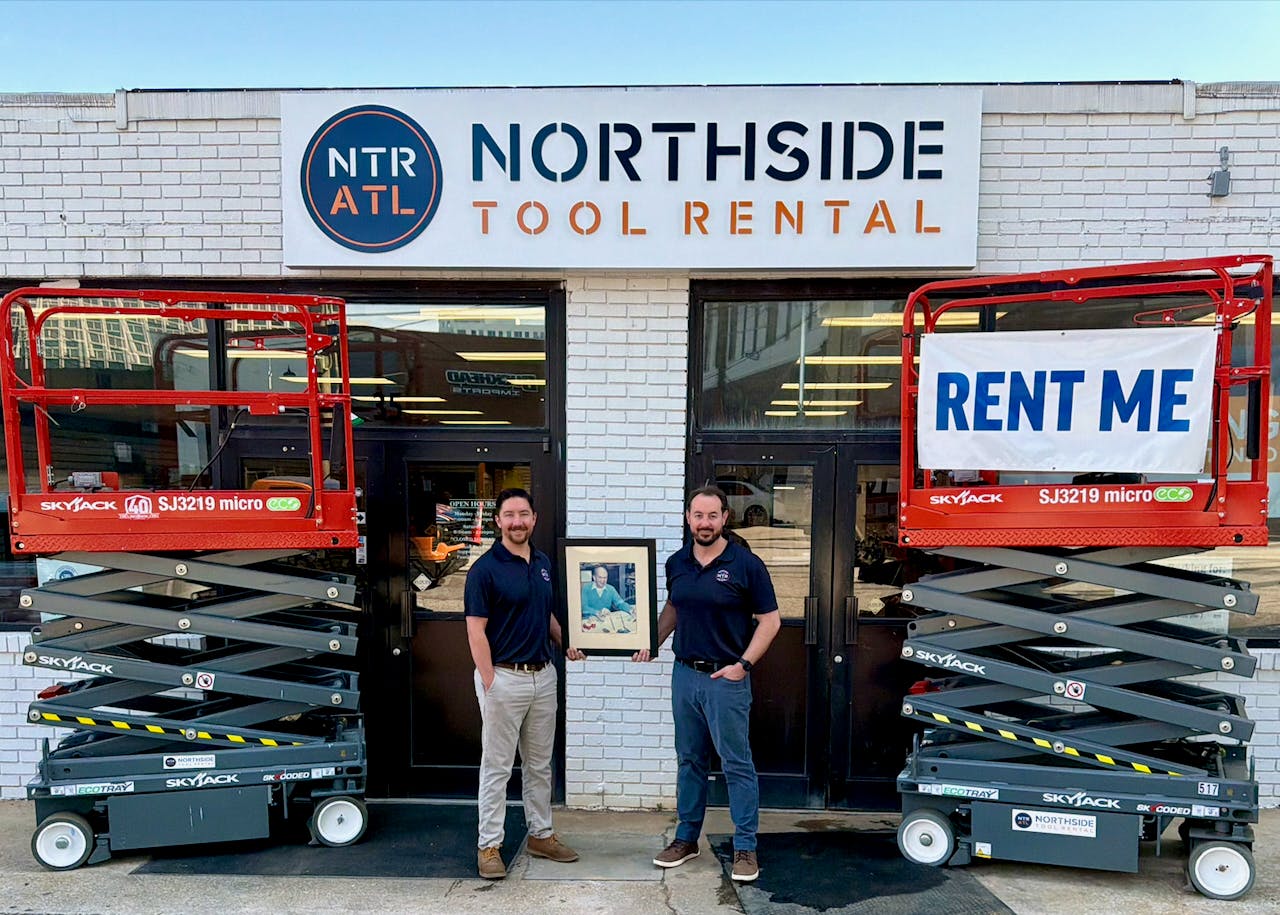 Cooper Douville, left, and Josh Nickell, hold up a photo of Northside Tool Rental founder Roy Milling.
