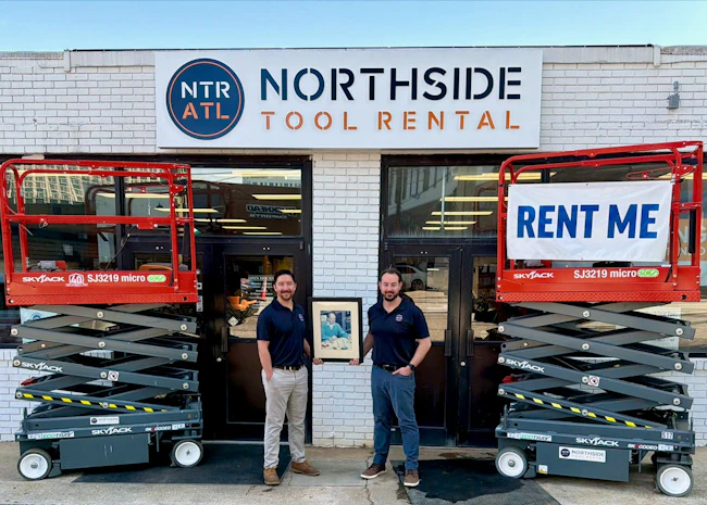 Cooper Douville, left, and Josh Nickell, hold up a photo of Northside Tool Rental founder Roy Milling.